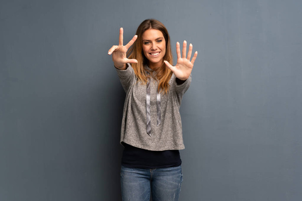 Ξανθιά γυναίκα πάνω από γκρι φόντο που μετράει οκτώ με τα δάχτυλα - Φωτογραφία, εικόνα