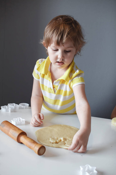 The child makes cookie molds on a white table. Preparation of homemade dessert - Fotoğraf, Görsel