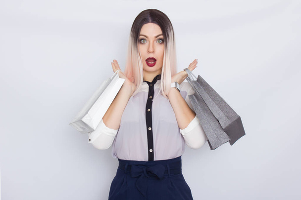 Mulher loira segurando sacos de compras em suas mãos
 - Foto, Imagem