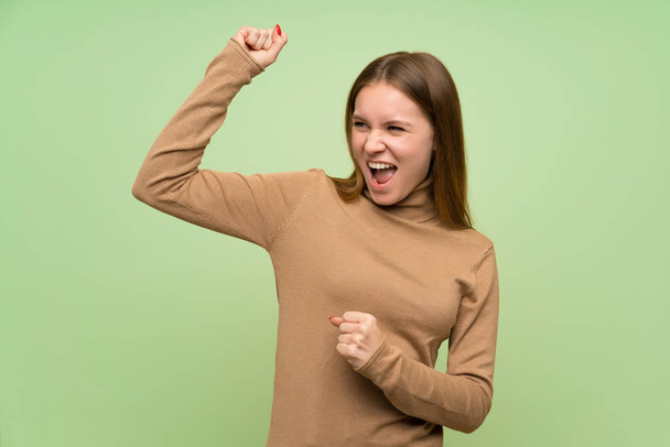 Νεαρή γυναίκα με ζιβάγκο πουλόβερ γιορτάζει μια νίκη - Φωτογραφία, εικόνα