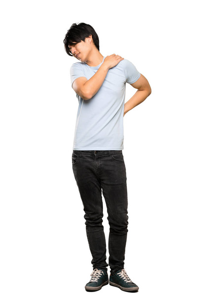 A full-length shot of a Asian man with blue shirt suffering from pain in shoulder for having made an effort over isolated white background - Foto, afbeelding
