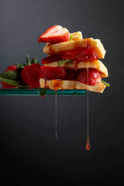 Βέλγικες βάφλες με φράουλες και μέλι γαρνιρισμένα με φρέσκα - Φωτογραφία, εικόνα