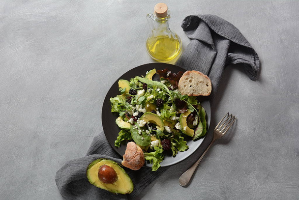 Avocado salad with lettuce, blackberry, blue cheese, olive oil and arugula on a plate. Healthy vegan food concept - Φωτογραφία, εικόνα