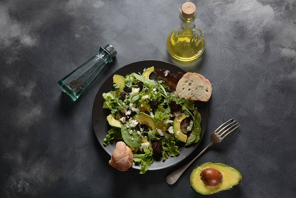 Avocado salad with lettuce, blackberry, blue cheese, olive oil and arugula on a plate. Healthy vegan food concept - Foto, Bild