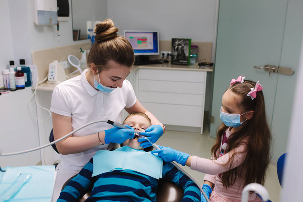 Μικρό κορίτσι βοήθεια θηλυκό οδοντίατρο, νέα οδοντισμός δοντιών και θεραπεία των κοιλοτήτων - Φωτογραφία, εικόνα