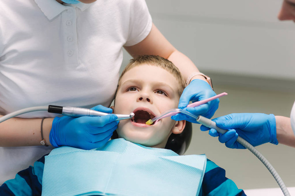 Młody chłopak siedzi na fotelu dentystycznym w biurze. Dzieci dentysta badanie zębów dla dzieci - Zdjęcie, obraz