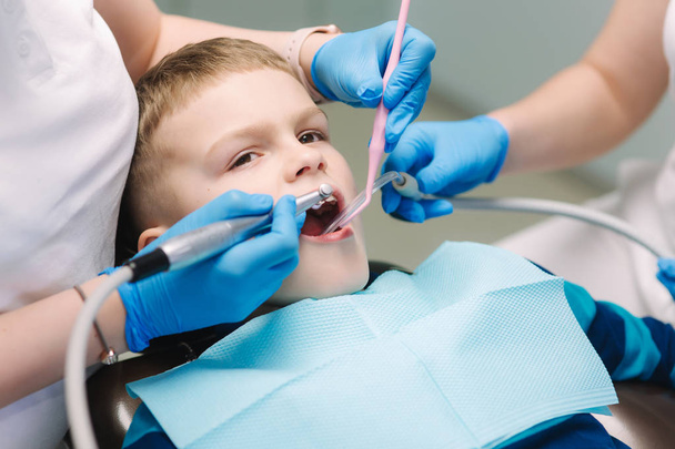 Young boy sitting on the dental chair at the office. Childrens dentist examination baby teeth - Valokuva, kuva