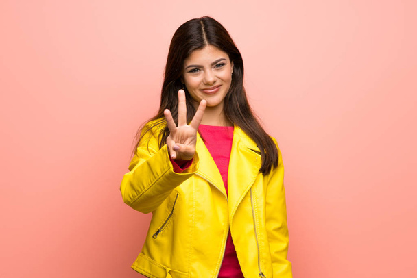 Teenager girl over pink wall happy and counting three with fingers - Foto, imagen