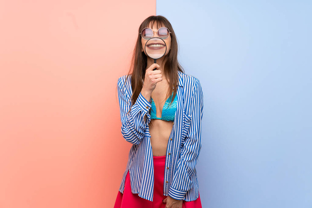 junge Frau im Bikini nimmt Vergrößerungsglas und zeigt Zähne - Foto, Bild