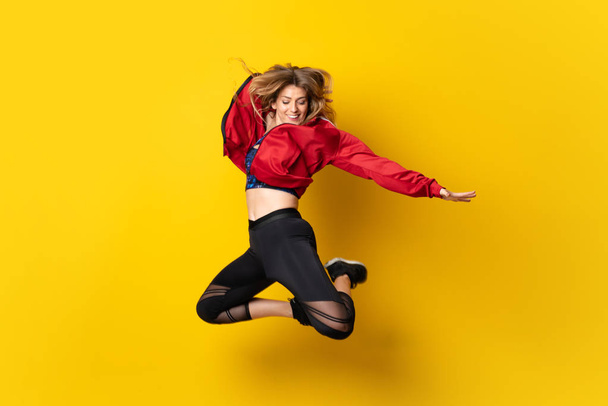 Urban Ballerina dancing over isolated yellow background and jumping - 写真・画像