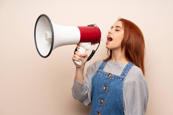 Young redhead woman over isolated background shouting through a megaphone - Foto, Imagen
