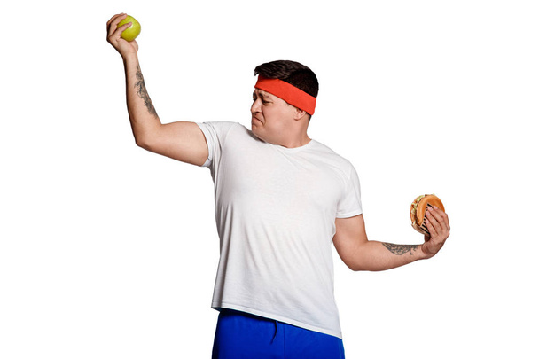 concept man makes the choice between healthy and unhealthy food. the choice between a burger and an apple. will power when dieting.  - Photo, image