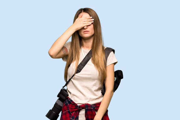 Young photographer woman covering eyes by hands. Do not want to see something on isolated blue background - Photo, Image