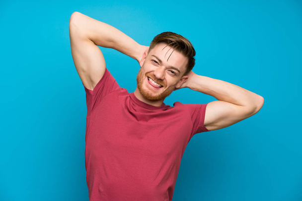 Κοκκινομάλλης άνθρωπος σε απομονωμένο μπλε τοίχο γέλιο - Φωτογραφία, εικόνα
