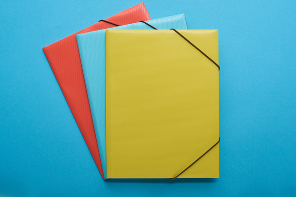Widok z góry na czerwone, niebieskie i żółte Segregatory papierowe izolowane na niebiesko - Zdjęcie, obraz