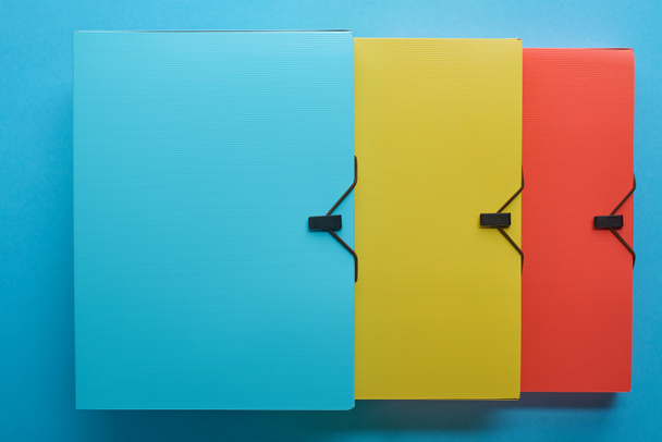 вид сверху разноцветных офисных бумажных папок на синий цвет
 - Фото, изображение