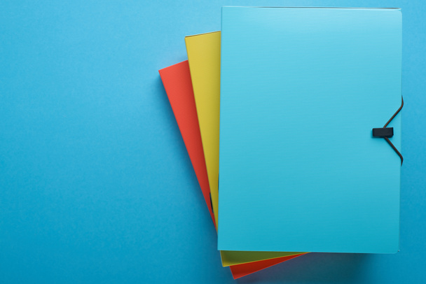top view of colorful paper binders isolated on blue with copy space - Photo, Image
