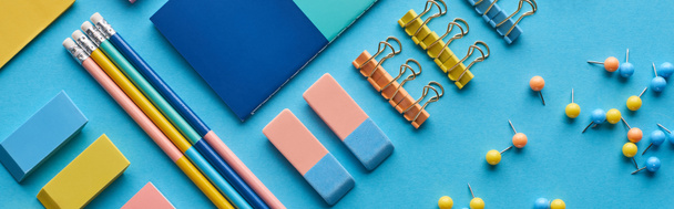 πανοραμική βολή από μολύβια, καρφίτσες push και πολύχρωμο επιστολόχαρτο απομονωθεί σε μπλε - Φωτογραφία, εικόνα