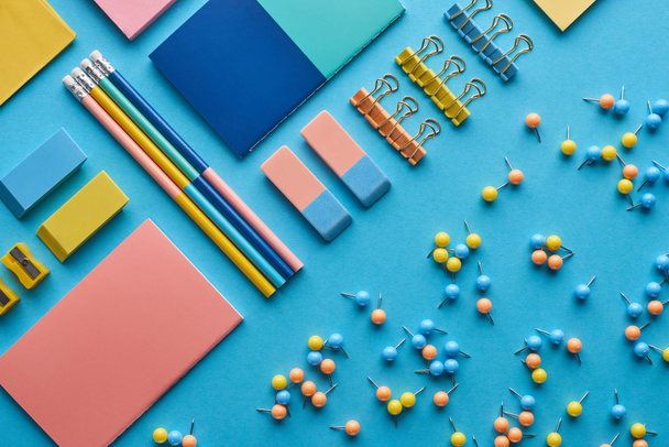 верхний вид ноутбуков и различных красочных канцелярских принадлежностей, изолированных на синий
 - Фото, изображение