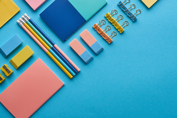 top view of notebooks and colorful stationery isolated on blue with copy space - Foto, afbeelding