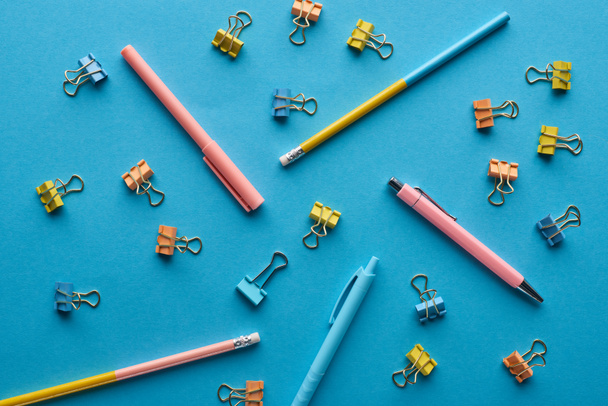 top view of pens, pencils and paper clips isolated on blue - Foto, immagini