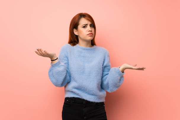 Young redhead woman over pink background unhappy and frustrated with something because not understand something - Photo, Image