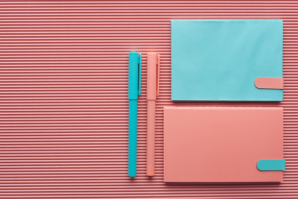 vista superior de canetas dispostas e cadernos em rosa texturizado com espaço de cópia
 - Foto, Imagem