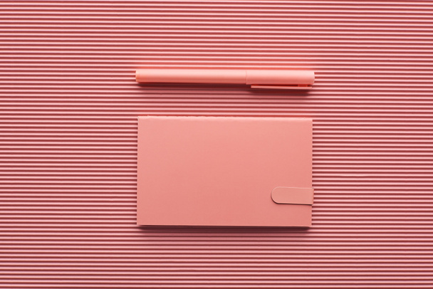 vista superior de la pluma y el bloc de notas en rosa texturizado
 - Foto, Imagen