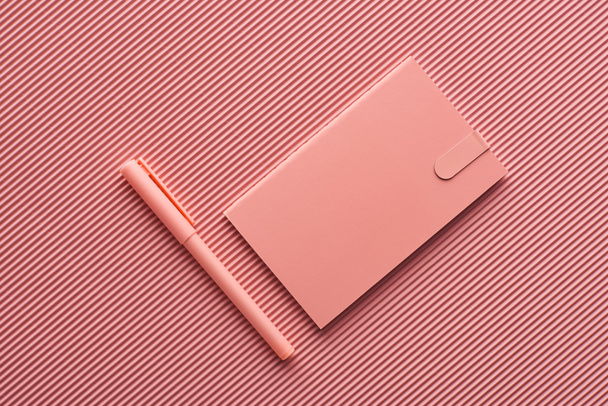 top view of pen and notebook on textured pink - Фото, зображення