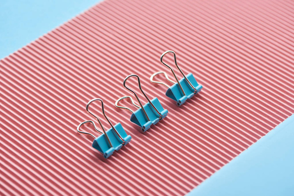 metal paper clips on textured pink paper isolated on blue - Photo, Image