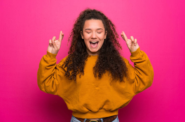 Ragazza adolescente sopra il muro rosa con le dita incrociate
 - Foto, immagini