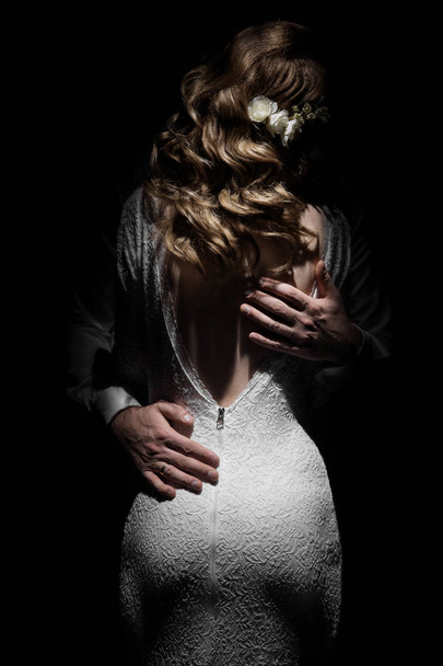bruid en bruidegom in de rug. Een man knuffels een meisje in een witte jurk. De handen van de bruidegom en de rug van de bruid. - Foto, afbeelding