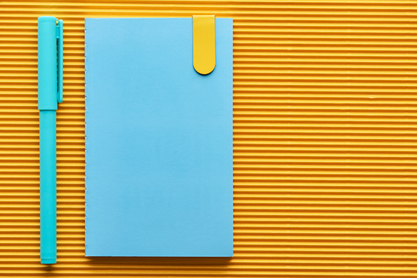 top view of blue pen and notebook on yellow with copy space - Fotografie, Obrázek