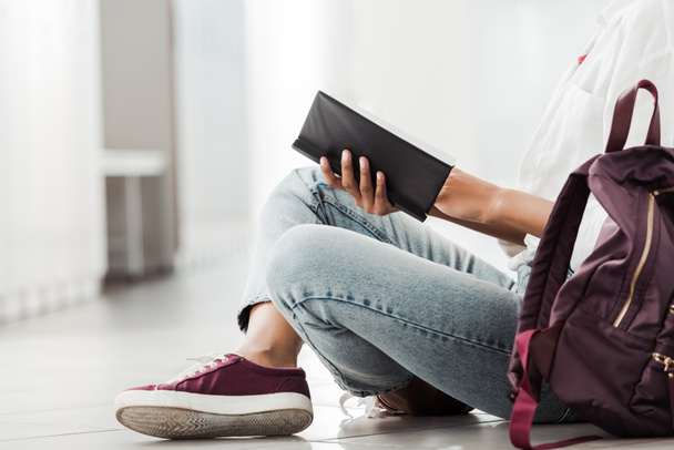 visão parcial do aluno com caderno sentado no chão
 - Foto, Imagem
