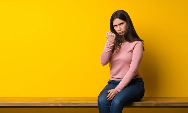 Jeune femme assise sur la table avec un geste de colère
 - Photo, image