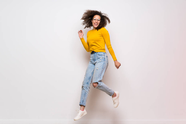 Dominican woman with curly hair jumping over isolated white background - Photo, Image