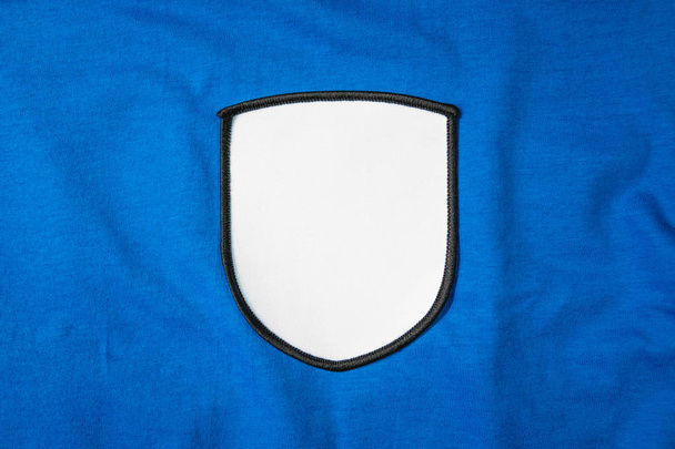 Lege arm patch op blauwe sportshirt. Wit team logo en embleem voor uw montage of bewerken. - Foto, afbeelding