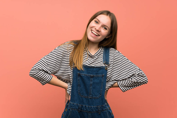 Young woman with overalls over pink wall smiling - Φωτογραφία, εικόνα