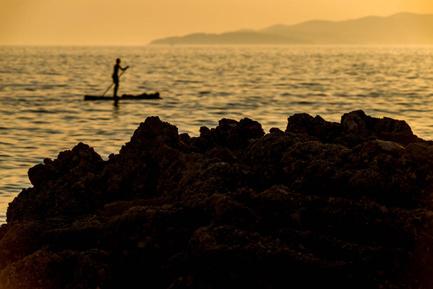 Silhouette of young couple on stand up paddle board. Active vaca - Photo, Image