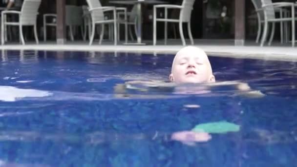 Przystojny chłopak blond pływa w The na wolnym powietrzu basen. - Materiał filmowy, wideo