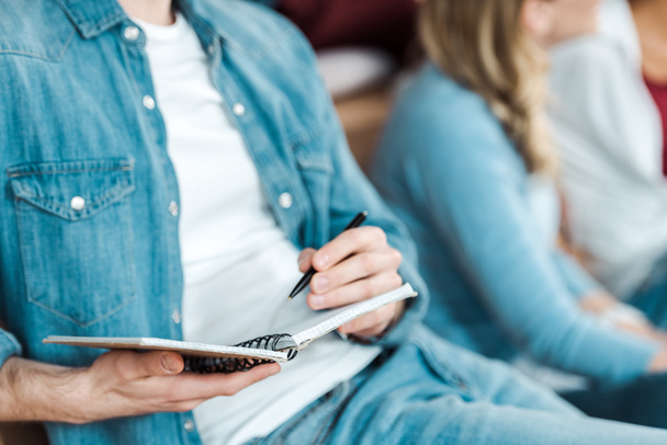 cropped view of student in denim shirt holding pen and notebook - Foto, Bild