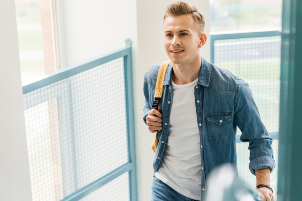 smiling student in denim shirt with backpack in college - Foto, Bild