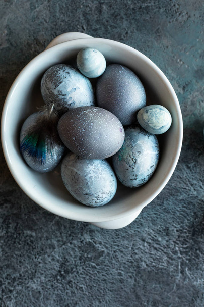 Összetétele húsvéti tojást egy tányérra egy szürke, kék textúrájú kő háttér. Térmásolat. Felülnézet. - Fotó, kép