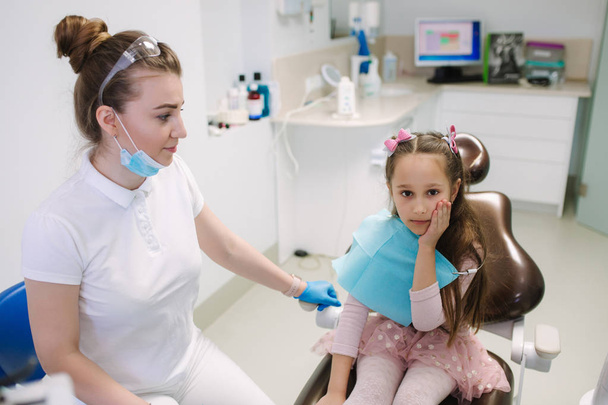 小さな女の子は歯が痛い。歯科医は患者を助ける - 写真・画像
