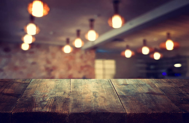 Image of wooden table in front of abstract blurred restaurant lights background - Foto, Bild
