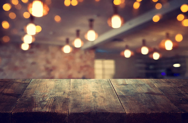 Image of wooden table in front of abstract blurred restaurant lights background - Photo, image