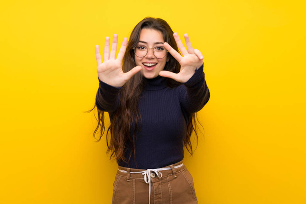 Дівчинка-підліток над ізольованою жовтою стіною, що підраховує дев'ять пальцями
 - Фото, зображення