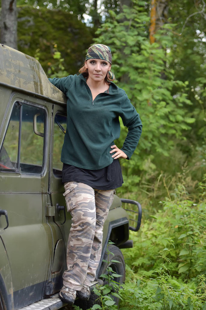 Woman wearing camouflage bandana against the backdrop of UAZ. - Φωτογραφία, εικόνα