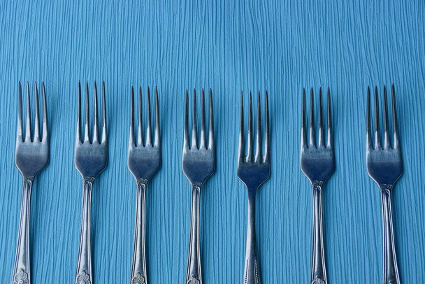 IJzeren grijze vorken op een blauwe tafel - Foto, afbeelding