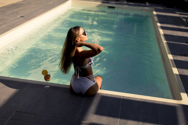 Красива молода жінка з випивкою на березі басейну в спекотний літній день
 - Фото, зображення
